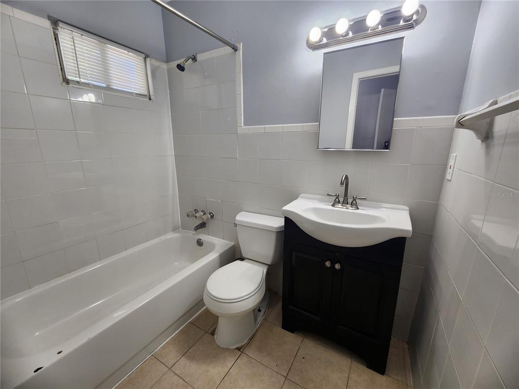 A bathroom features a white bathtub, a toilet, and a dark vanity with a sink — 1512 W 31ST STREET, JACKSONVILLE, FL