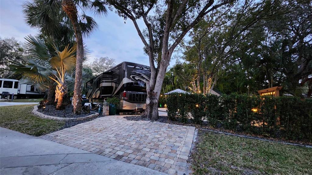 A large motorhome is parked on a paved lot surrounded by trees and landscaping — 140 APPALOOSA TRAIL, RIVER RANCH, FL