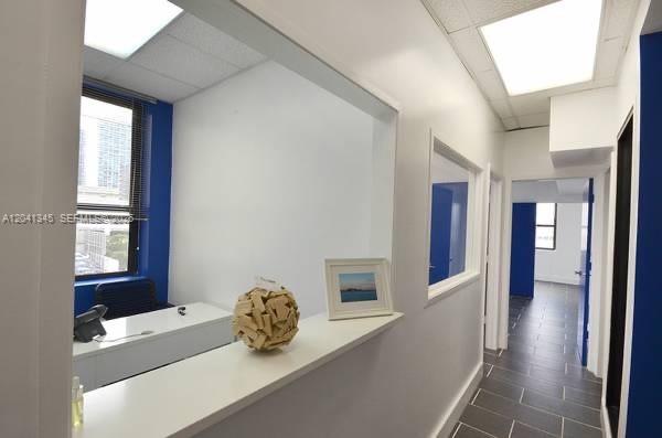 An office interior features a white desk, a decorative sphere, and a hallway with tile flooring — 168 SE 1st St # 501, Miami FL 33131, MIAMI, FL