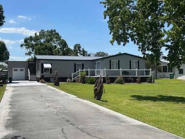 A gray manufactured home features a white porch, a concrete driveway, and a detached garage — 4031 SW 9th Way, Okeechobee FL 34974, OKEECHOBEE, FL