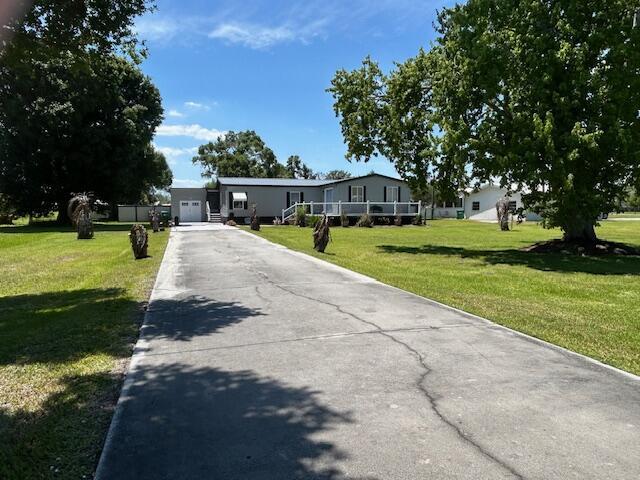 A long concrete driveway leads to a single-story house with a white garage — 4031 SW 9th Way, Okeechobee FL 34974, OKEECHOBEE, FL