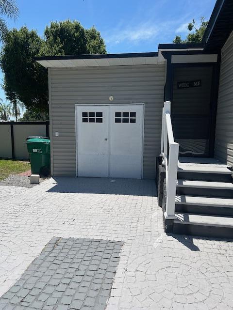 A gray exterior wall features white double doors, a side staircase, and a paved patio — 4031 SW 9th Way, Okeechobee FL 34974, OKEECHOBEE, FL