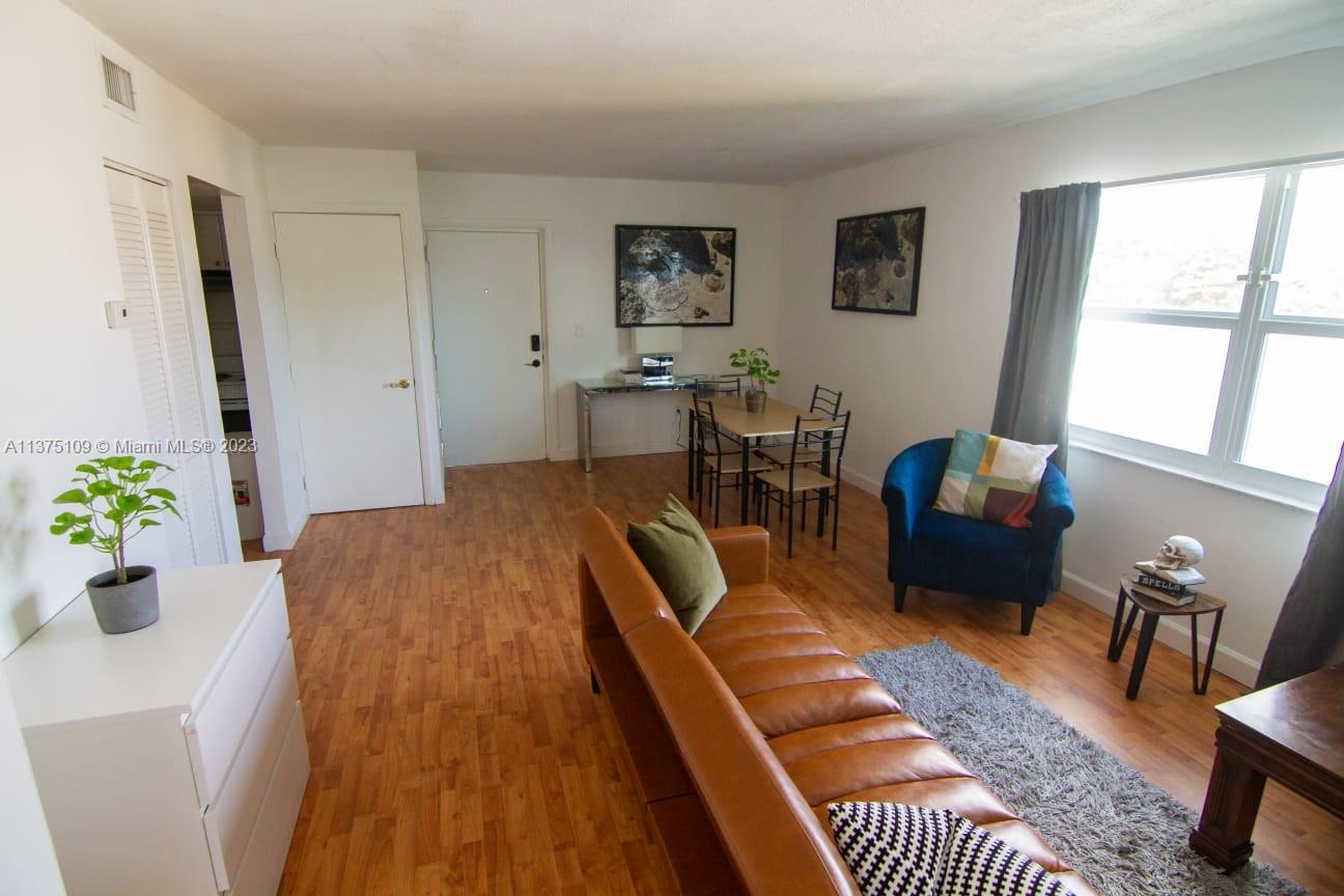 A living and dining area features wood-look flooring, a leather sofa, and a blue armchair — 753 Michigan Ave # 3D, Miami Beach FL 33139, MIAMI BEACH, FL