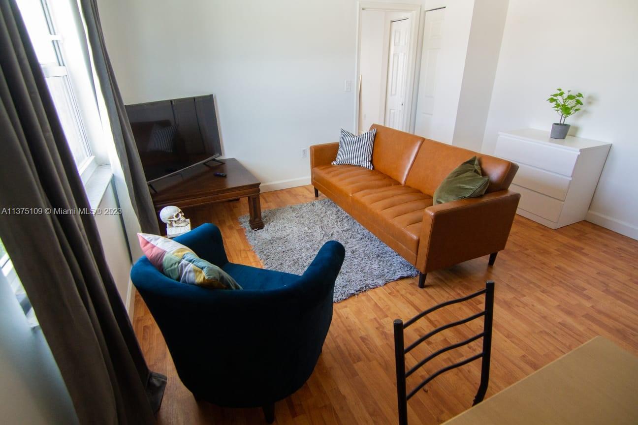 A living room features a brown leather sofa, a blue armchair, and a television stand — 753 Michigan Ave # 3D, Miami Beach FL 33139, MIAMI BEACH, FL