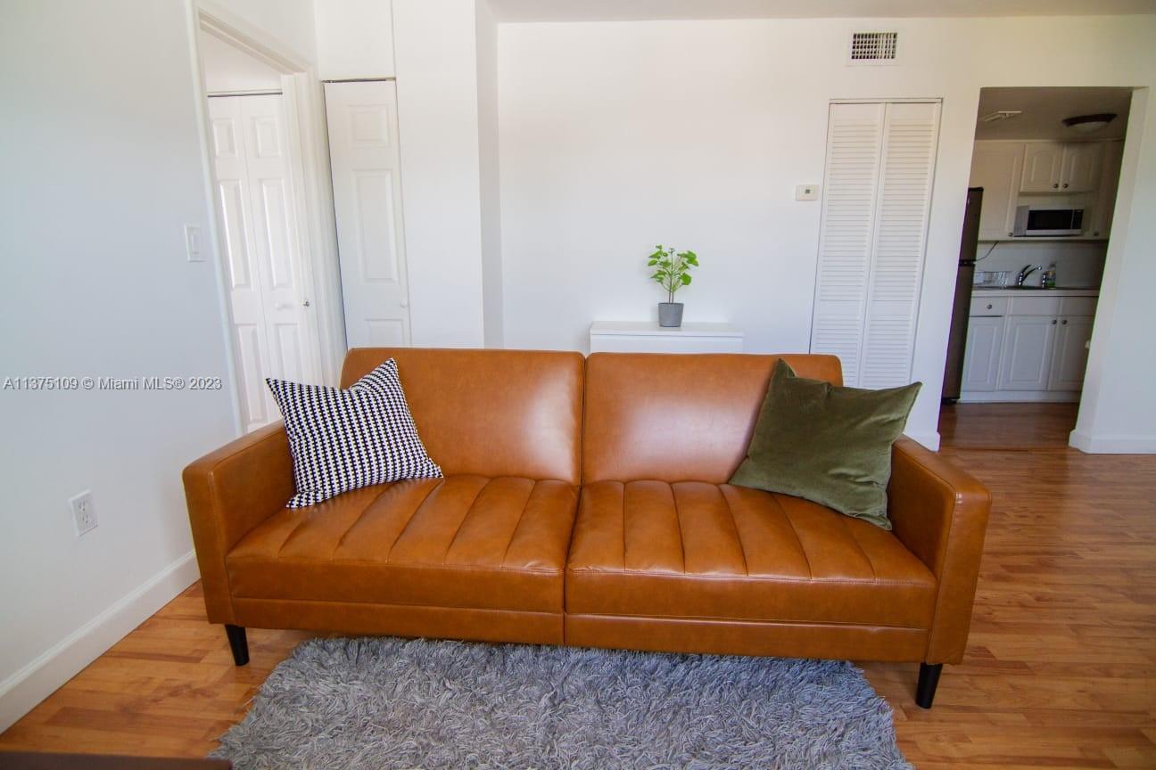 A brown leather sofa sits on a gray rug in a room with white walls — 753 Michigan Ave # 3D, Miami Beach FL 33139, MIAMI BEACH, FL