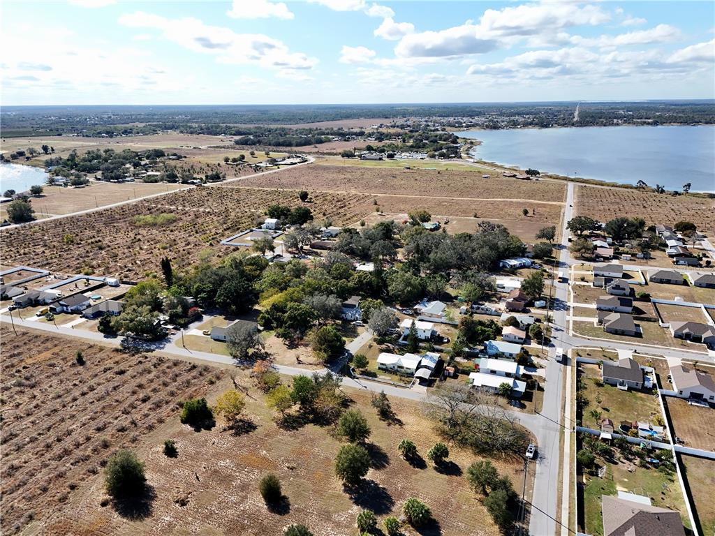 An aerial view shows a residential neighborhood with scattered houses, trees, and a nearby lake — FLORIDA STREET, FROSTPROOF, FL