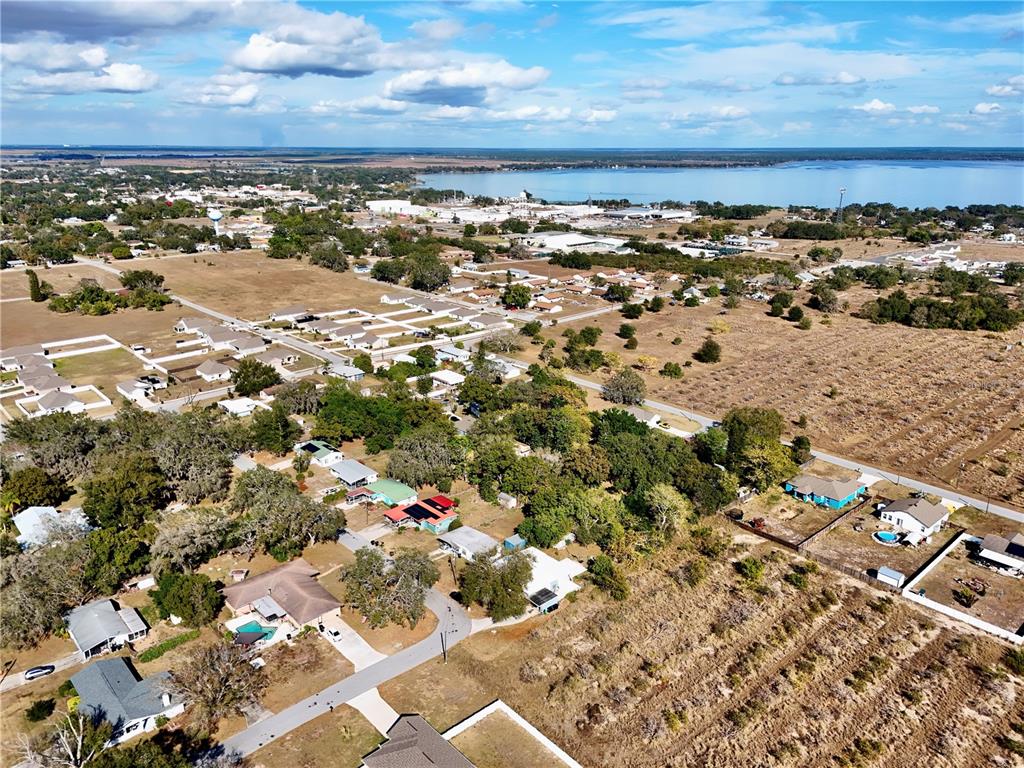 An aerial view shows a residential neighborhood with scattered houses, trees, and a distant lake — FLORIDA STREET, FROSTPROOF, FL