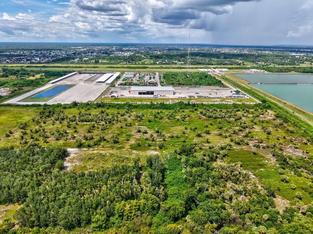 An aerial view shows a large industrial facility with surrounding land, vegetation, and water retention ponds — 3317 ROWLAND DRIVE UNIT Tract F, PUNTA GORDA, FL