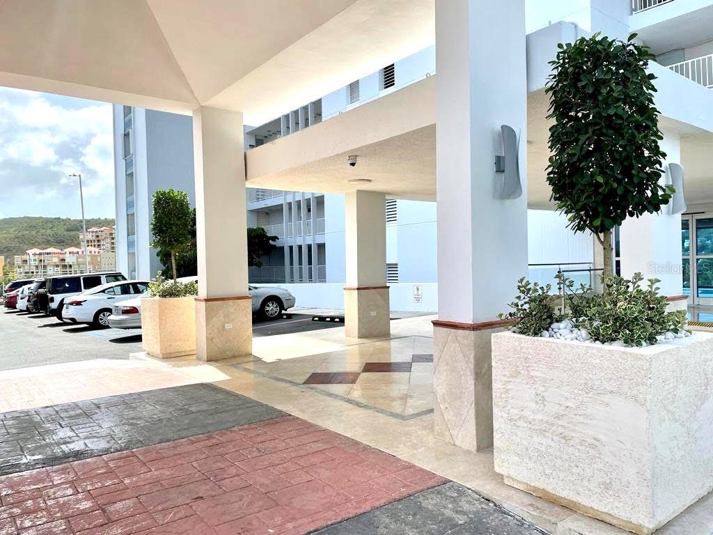 A covered building entrance features stone planters, tiled flooring, and a parking area — 200 AVE MARINA VIEW DOS MARINAS II CONDOMINIUM UNIT 2307, FAJARDO, PR