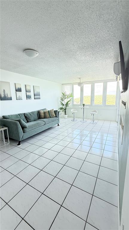 A living room features a teal sofa, white tile flooring, and large windows with views — 200 AVE MARINA VIEW DOS MARINAS II CONDOMINIUM UNIT 2307, FAJARDO, PR