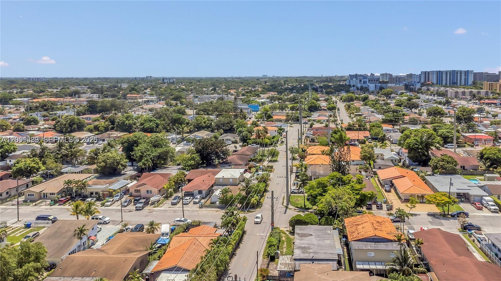 An aerial view shows a residential neighborhood with single-family homes, tree-lined streets, and distant buildings — 503 NW 43rd Pl, Miami FL 33126, MIAMI, FL