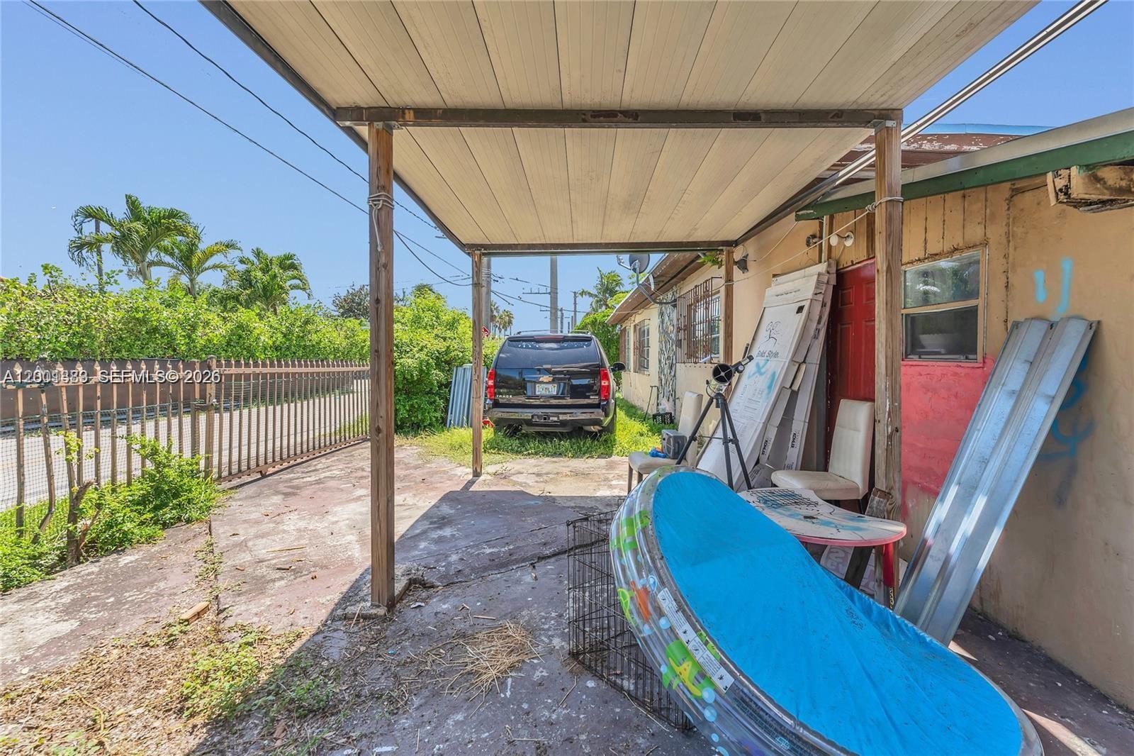 A covered carport area features a parked SUV, a small pool, and various stored items — 503 NW 43rd Pl, Miami FL 33126, MIAMI, FL