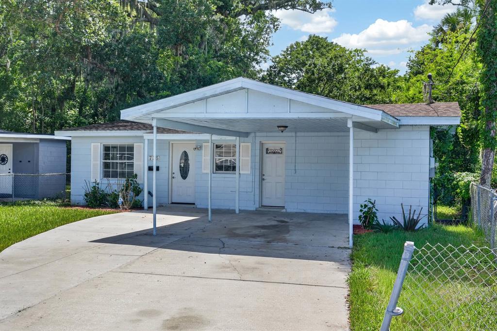 A light blue single-story house features a concrete driveway and an attached front carport — 736 S CAROLINE STREET, DAYTONA BEACH, FL