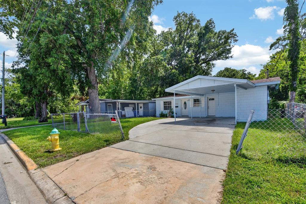 A light blue single-story house with a carport sits behind a chain-link fence — 736 S CAROLINE STREET, DAYTONA BEACH, FL