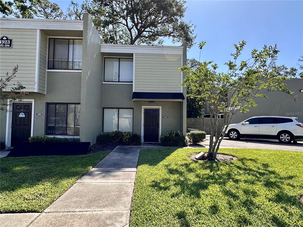 A two-story townhouse exterior features two dark entry doors, light siding, and a concrete walkway — 4923 25TH STREET W UNIT 104, BRADENTON, FL