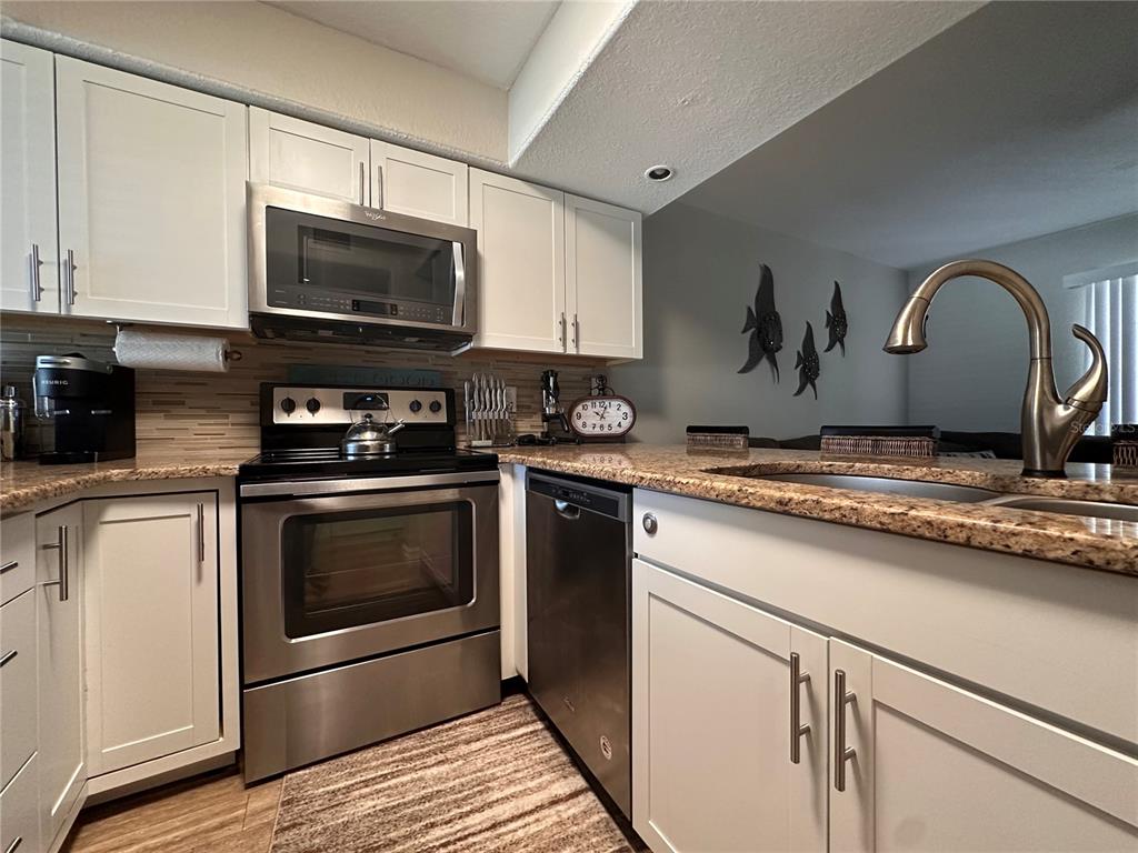 A kitchen features white cabinets, stainless steel appliances, and granite countertops — 4923 25TH STREET W UNIT 104, BRADENTON, FL