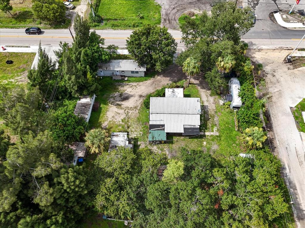 An aerial view shows a property with multiple small structures, trees, and a gravel driveway — 9890 ORANGE RIVER BOULEVARD, FORT MYERS, FL