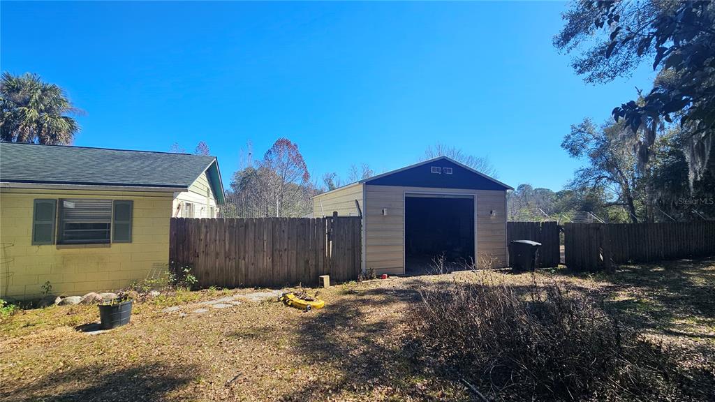 A yellow house and a detached metal garage stand in a yard with a fence — 43734 WEST LANE, PAISLEY, FL