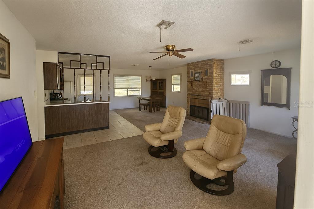 A living room with beige carpet, two tan leather recliners, and a brick fireplace — 43734 WEST LANE, PAISLEY, FL
