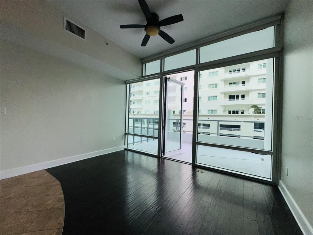 An empty room with dark wood flooring, a ceiling fan, and floor-to-ceiling windows leading outside — 101 S EOLA DRIVE UNIT 518, ORLANDO, FL
