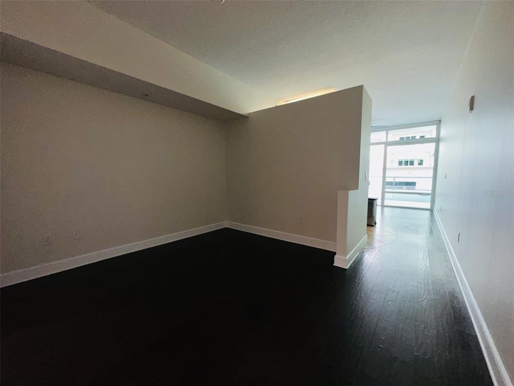 An empty room with dark wood flooring and a partial wall leading to a balcony — 101 S EOLA DRIVE UNIT 518, ORLANDO, FL