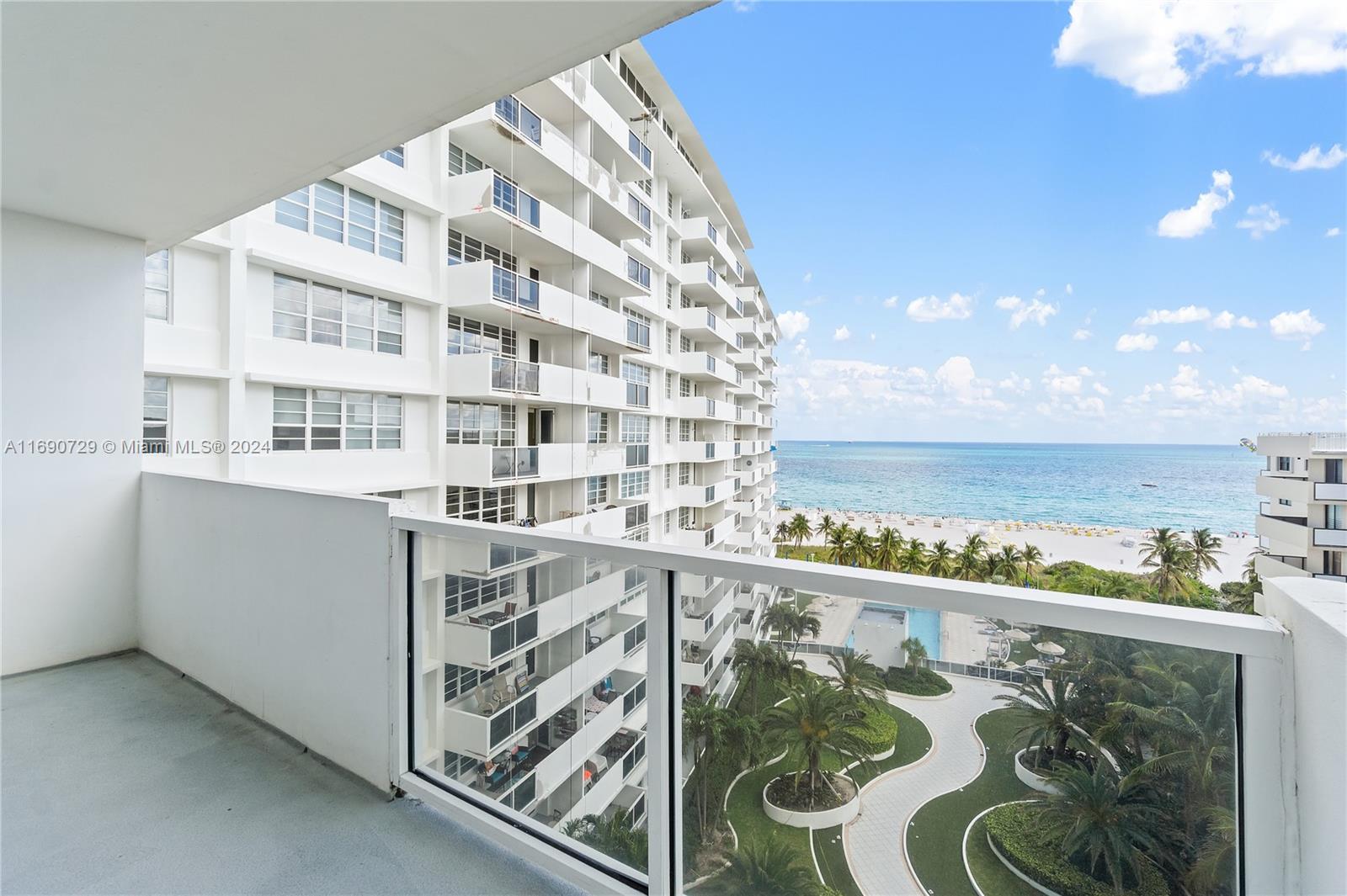 A balcony view overlooks a large white apartment building, a swimming pool, and the ocean — 100 Lincoln Rd # 1019, Miami Beach FL 33139, MIAMI BEACH, FL