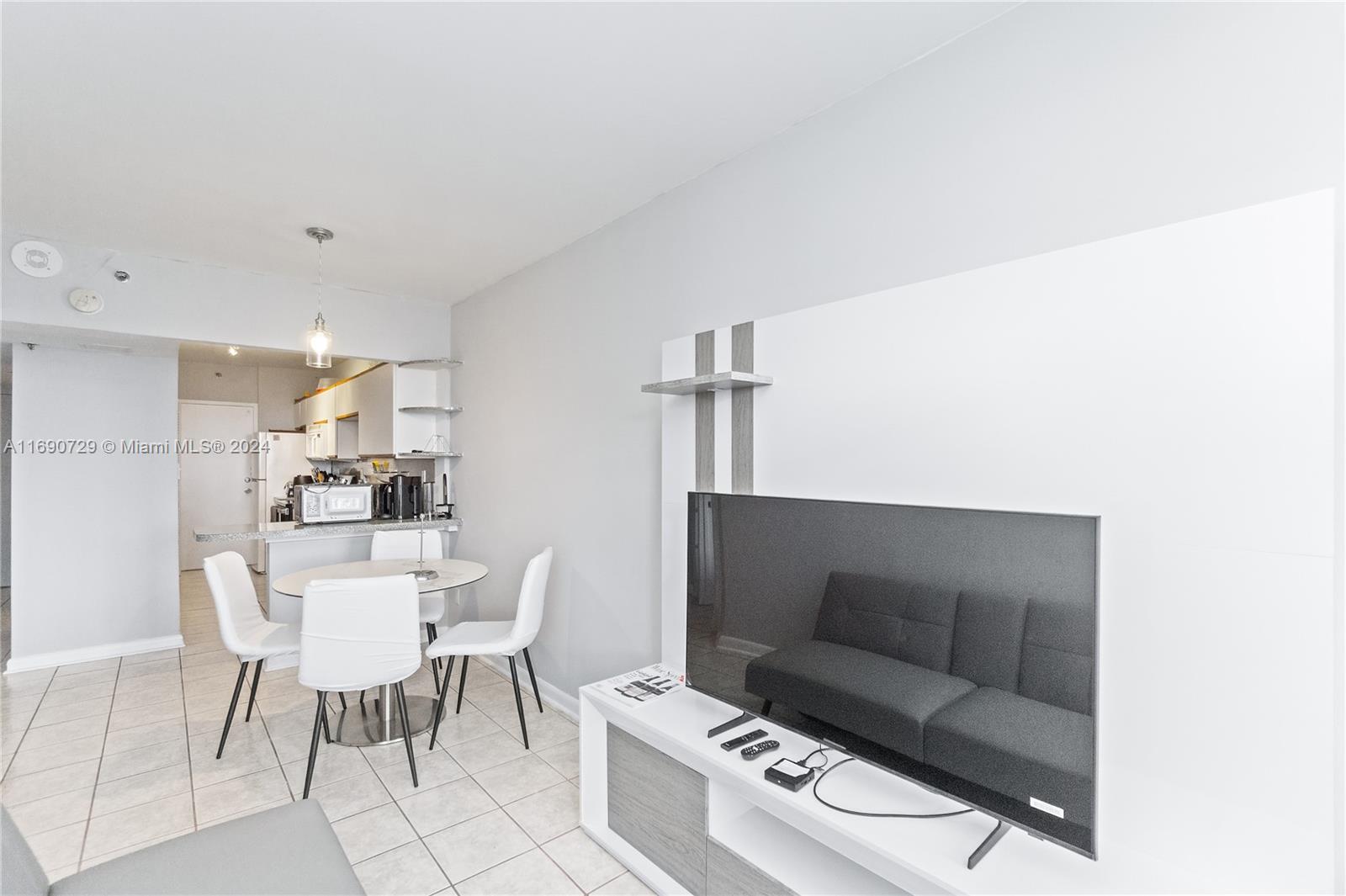 A living room with a wall-mounted television, a dining set, and an adjacent kitchen area — 100 Lincoln Rd # 1019, Miami Beach FL 33139, MIAMI BEACH, FL