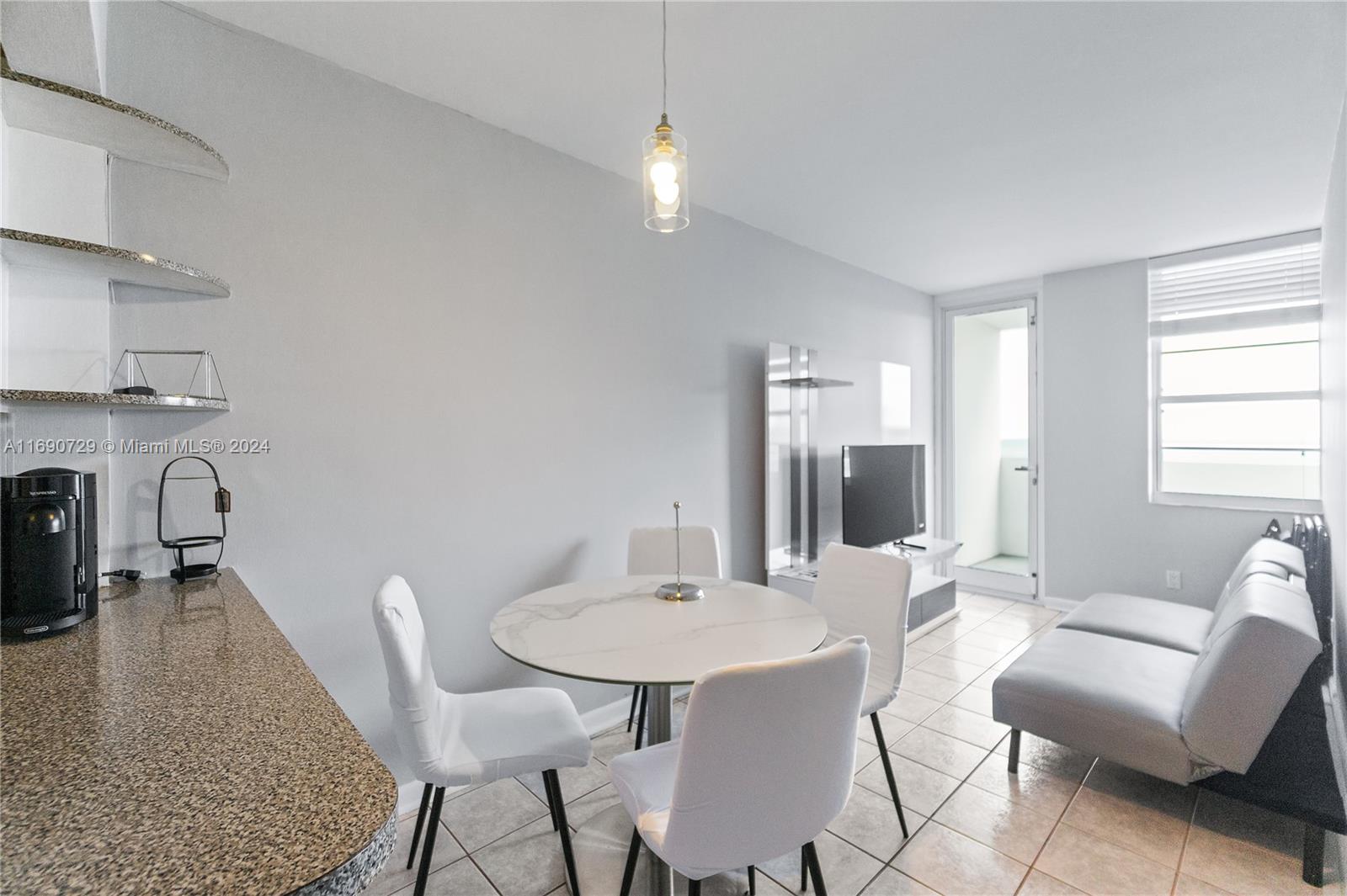 A small dining area with a round table and chairs sits next to a living space — 100 Lincoln Rd # 1019, Miami Beach FL 33139, MIAMI BEACH, FL