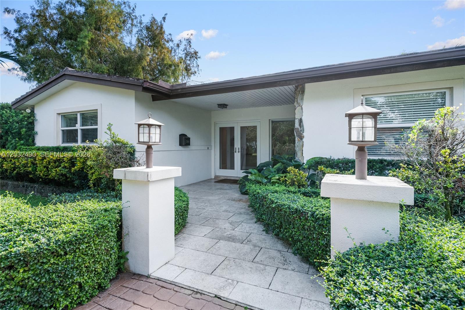A stone walkway leads to the front entrance of a house with white exterior walls — 7360 SW 115th St, Pinecrest FL 33156, PINECREST, FL