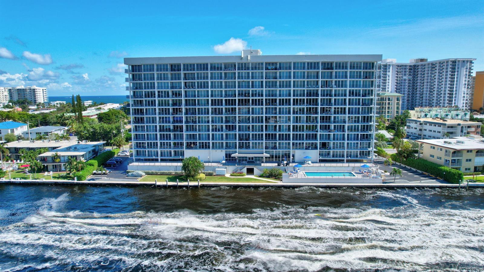 An aerial view of a multi-story residential building with a pool located beside a waterway — 521 N Riverside Drive # 1207, Pompano Beach FL 33062, POMPANO BEACH, FL
