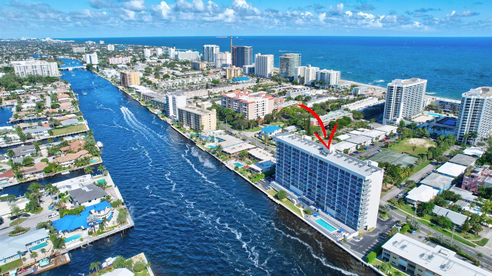 An aerial view shows a tall residential building beside a canal near the ocean — 521 N Riverside Drive # 1207, Pompano Beach FL 33062, POMPANO BEACH, FL