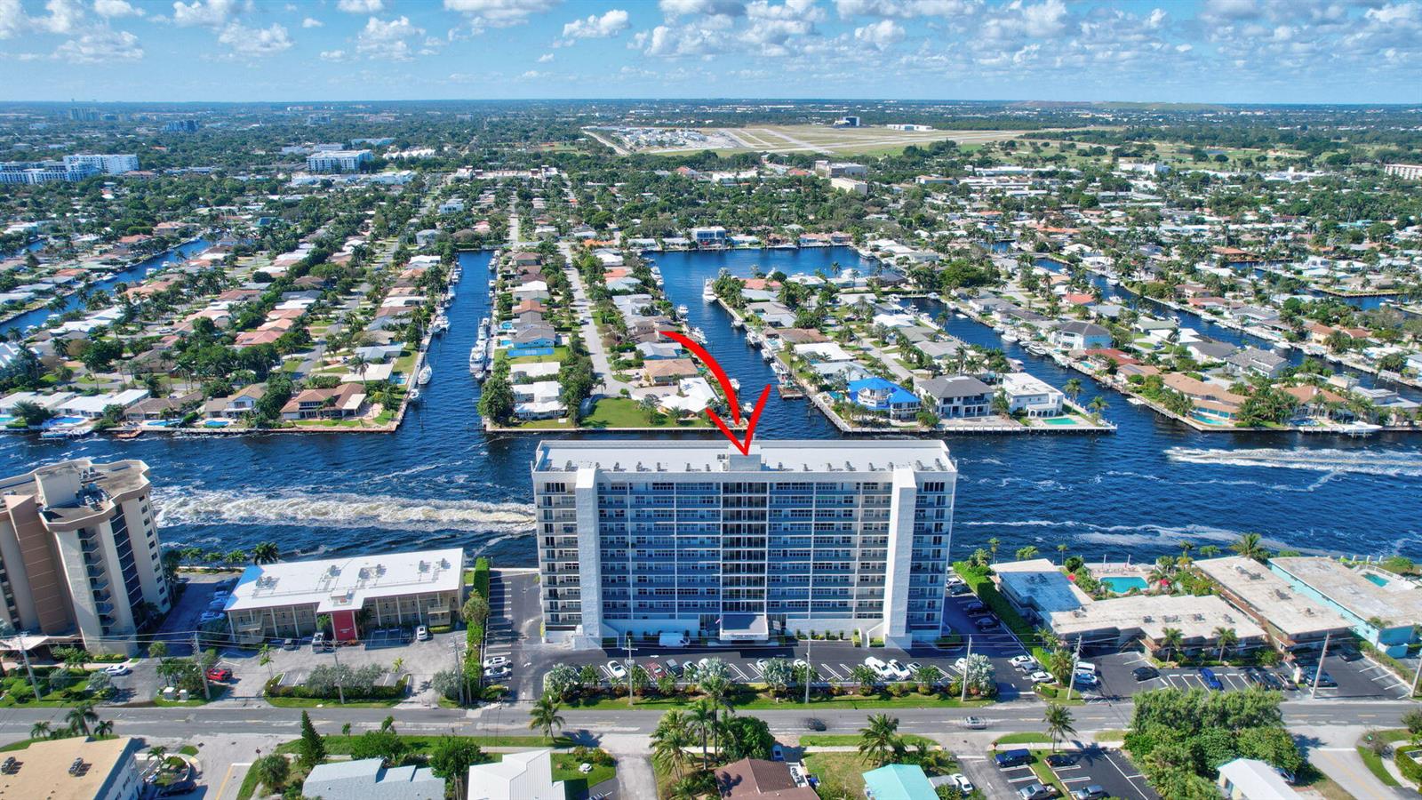 An aerial view shows a tall residential building situated along a canal in a neighborhood — 521 N Riverside Drive # 1207, Pompano Beach FL 33062, POMPANO BEACH, FL