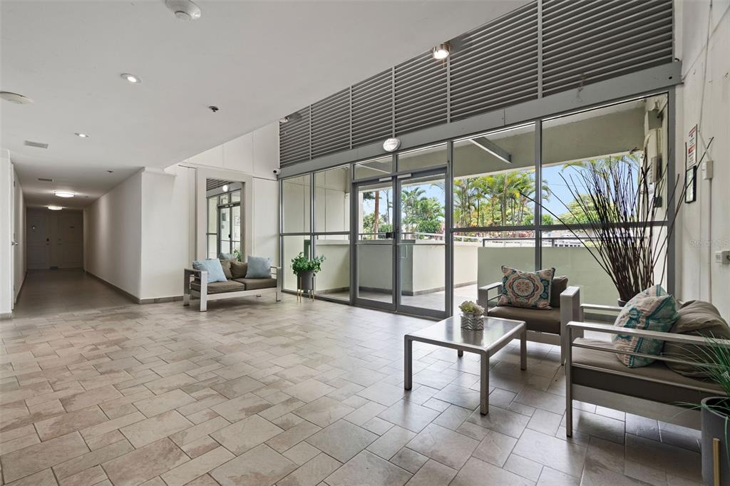 A tiled lobby features a seating area with chairs, a sofa, and glass sliding doors — 37 Atrium Park CALLE REGINA MEDINA UNIT C-604, GUAYNABO, PR