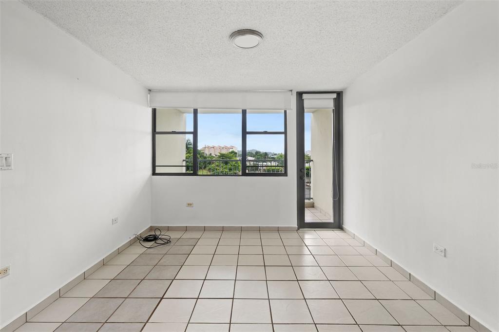 An empty room with white walls, light-colored tile flooring, large windows, and a balcony door — 37 Atrium Park CALLE REGINA MEDINA UNIT C-604, GUAYNABO, PR