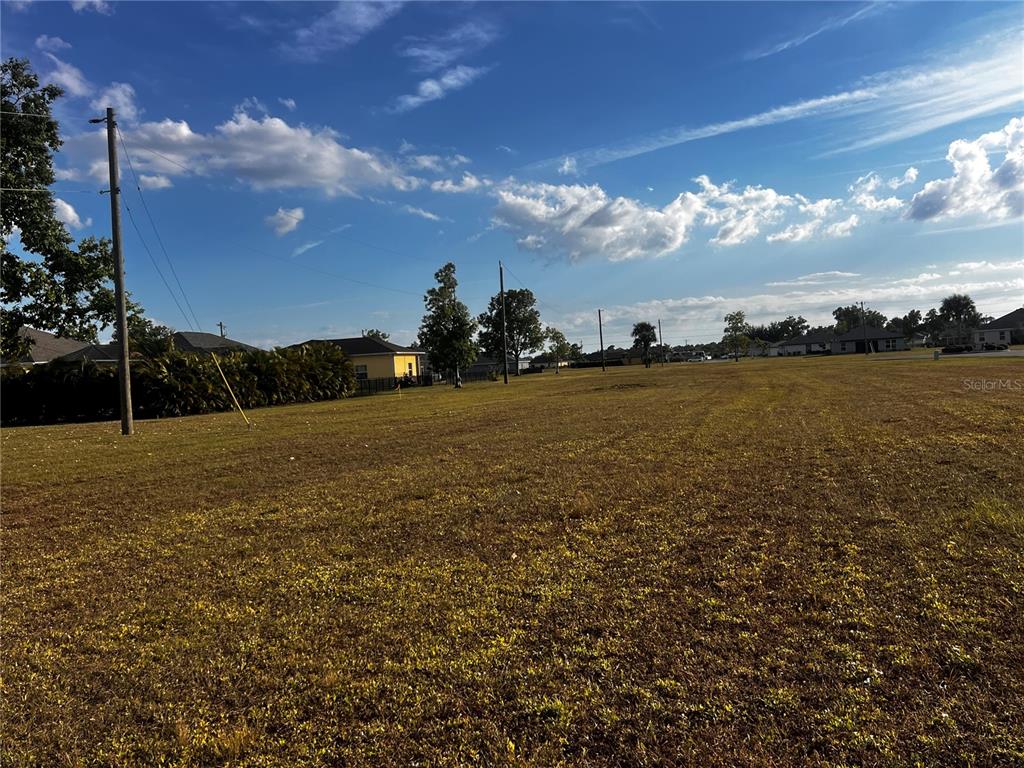 A large, grassy vacant lot under a blue sky with scattered clouds — 25458 ISLAS DRIVE, PUNTA GORDA, FL