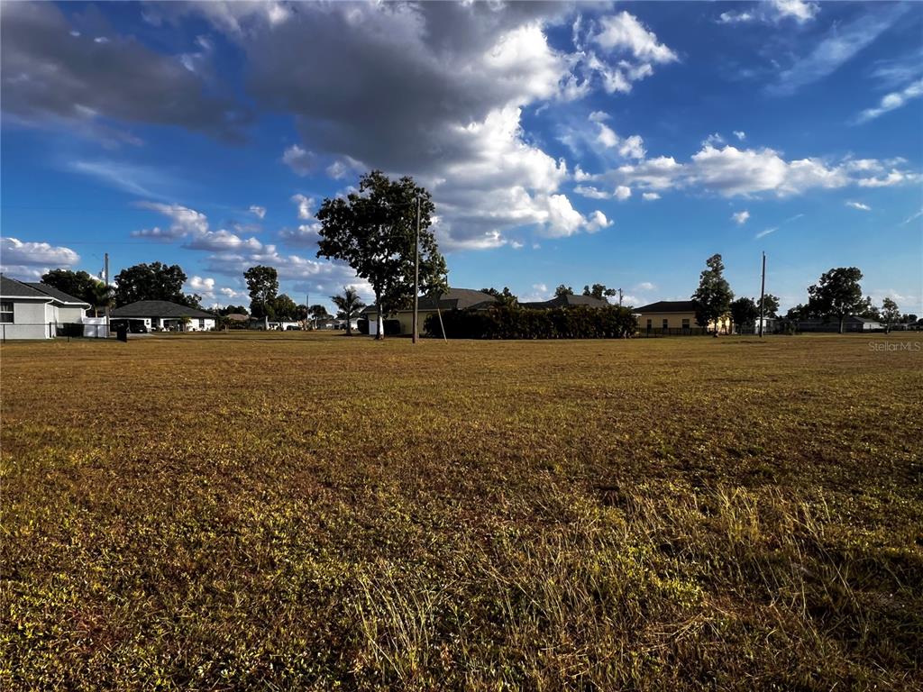 A wide, grassy vacant lot under a blue sky with scattered clouds — 25458 ISLAS DRIVE, PUNTA GORDA, FL