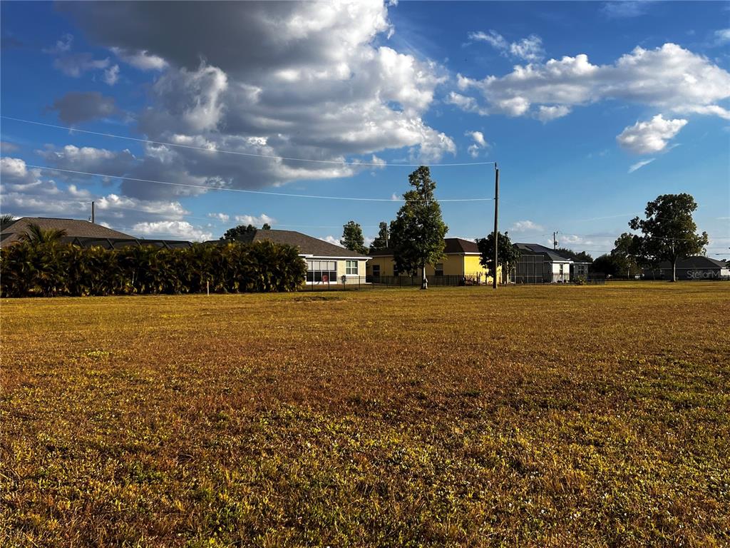 A large, flat, grassy vacant lot sits in front of several suburban houses — 25458 ISLAS DRIVE, PUNTA GORDA, FL