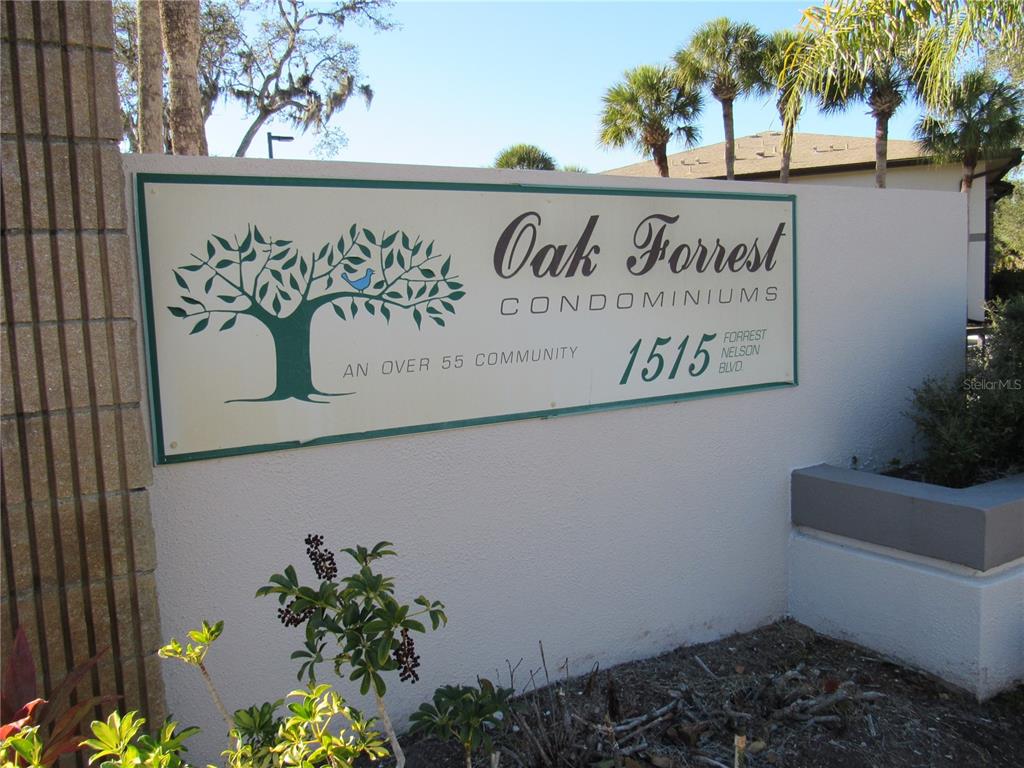 A sign for Oak Forrest Condominiums stands on a wall in an outdoor setting — 1515 FORREST NELSON BOULEVARD UNIT N201, PORT CHARLOTTE, FL