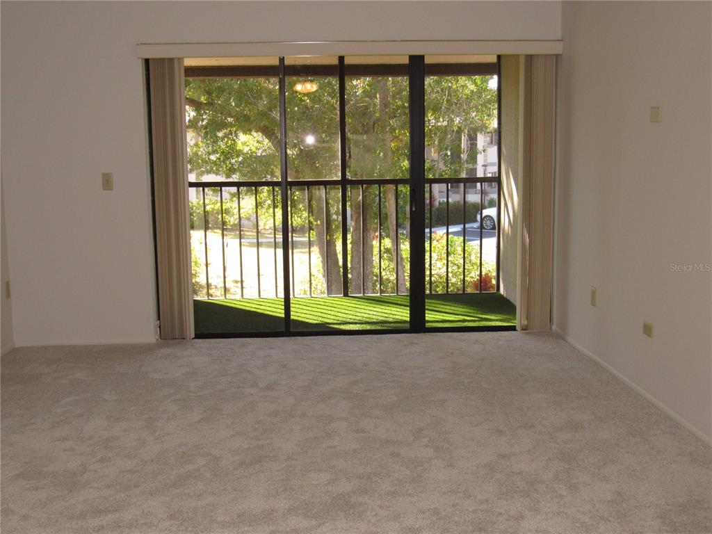 A carpeted room features a large sliding glass door opening onto a screened-in balcony — 1515 FORREST NELSON BOULEVARD UNIT N201, PORT CHARLOTTE, FL