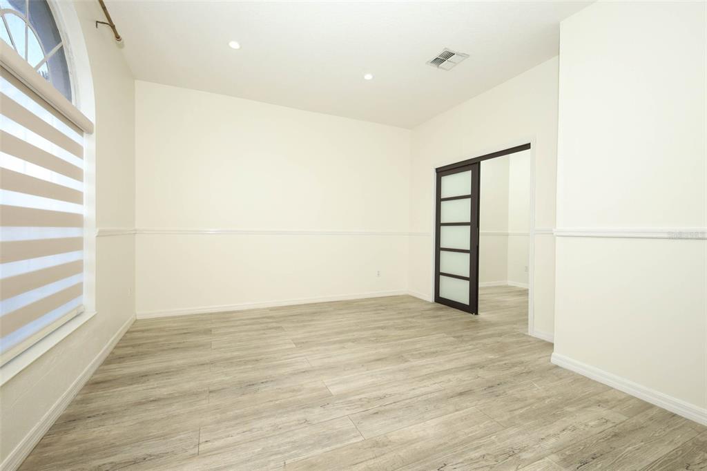 An empty room with light wood-look flooring, white walls, a window, and a sliding door — 9345 MONTEREY BAY DRIVE, ORLANDO, FL