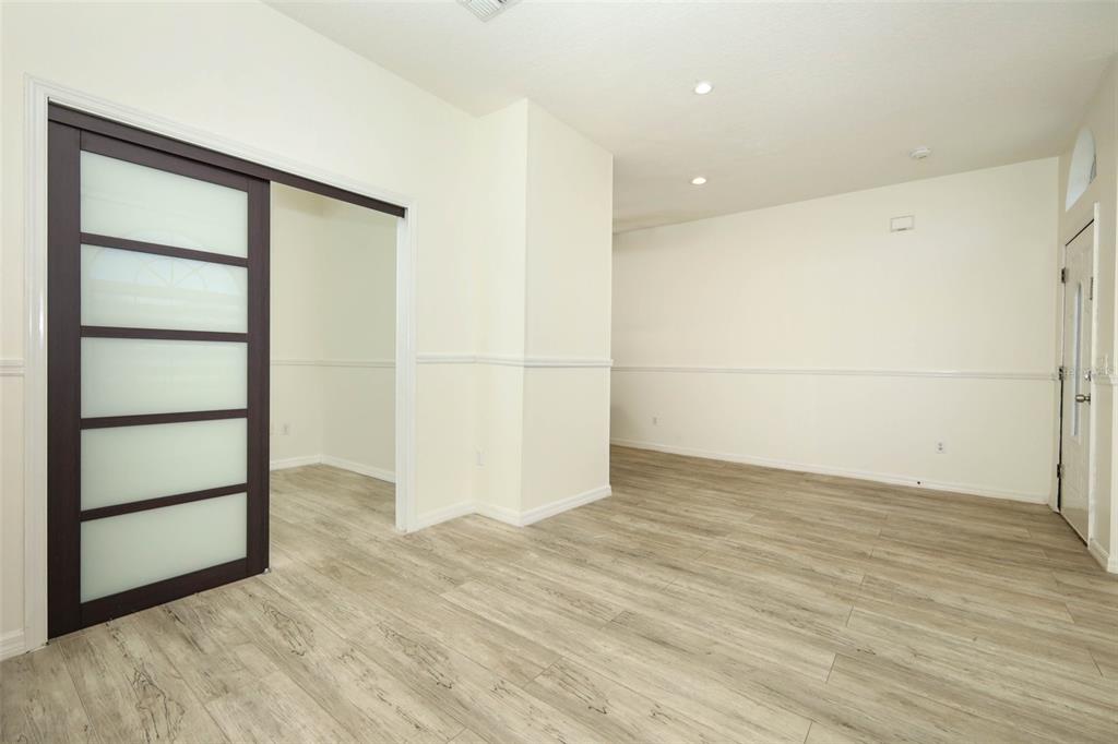 A room with light wood-look flooring, white walls with chair rail molding, and a sliding door — 9345 MONTEREY BAY DRIVE, ORLANDO, FL