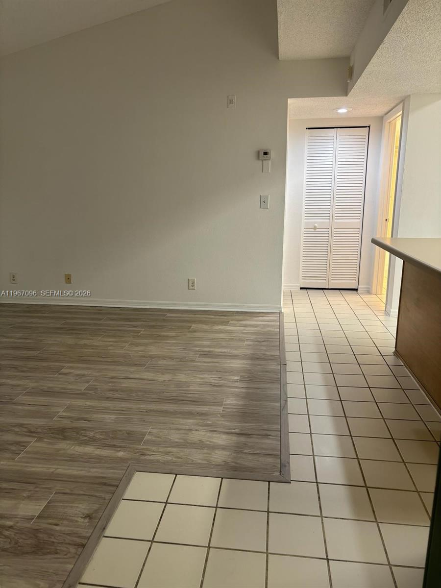 A room features wood-look flooring transitioning to white tiles near a louvered closet door — 3985 W Mcnab Rd # A302, Pompano Beach FL 33069, POMPANO BEACH, FL