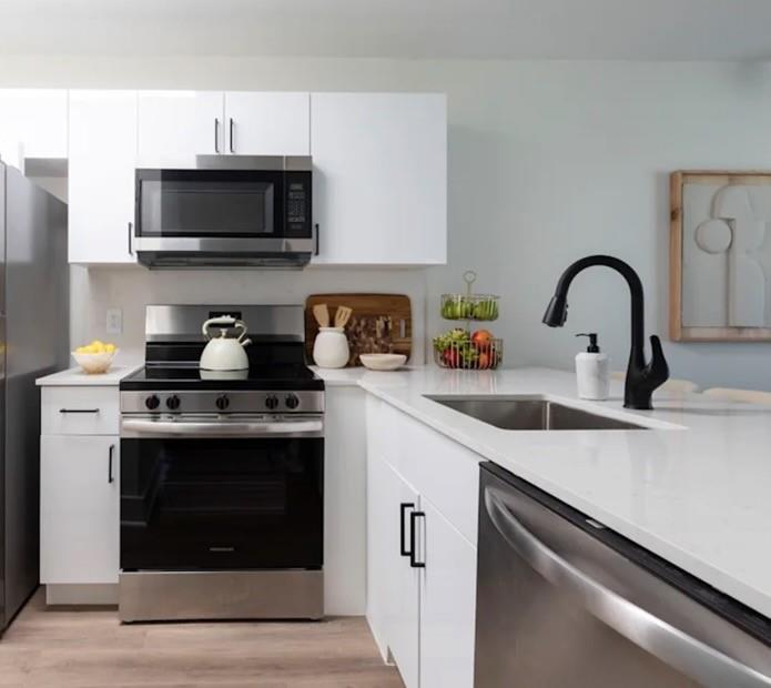 A modern kitchen features white cabinets, stainless steel appliances, and a white quartz countertop — 800 The Pointe Drive, West Palm Beach FL 33409, WEST PALM BEACH, FL
