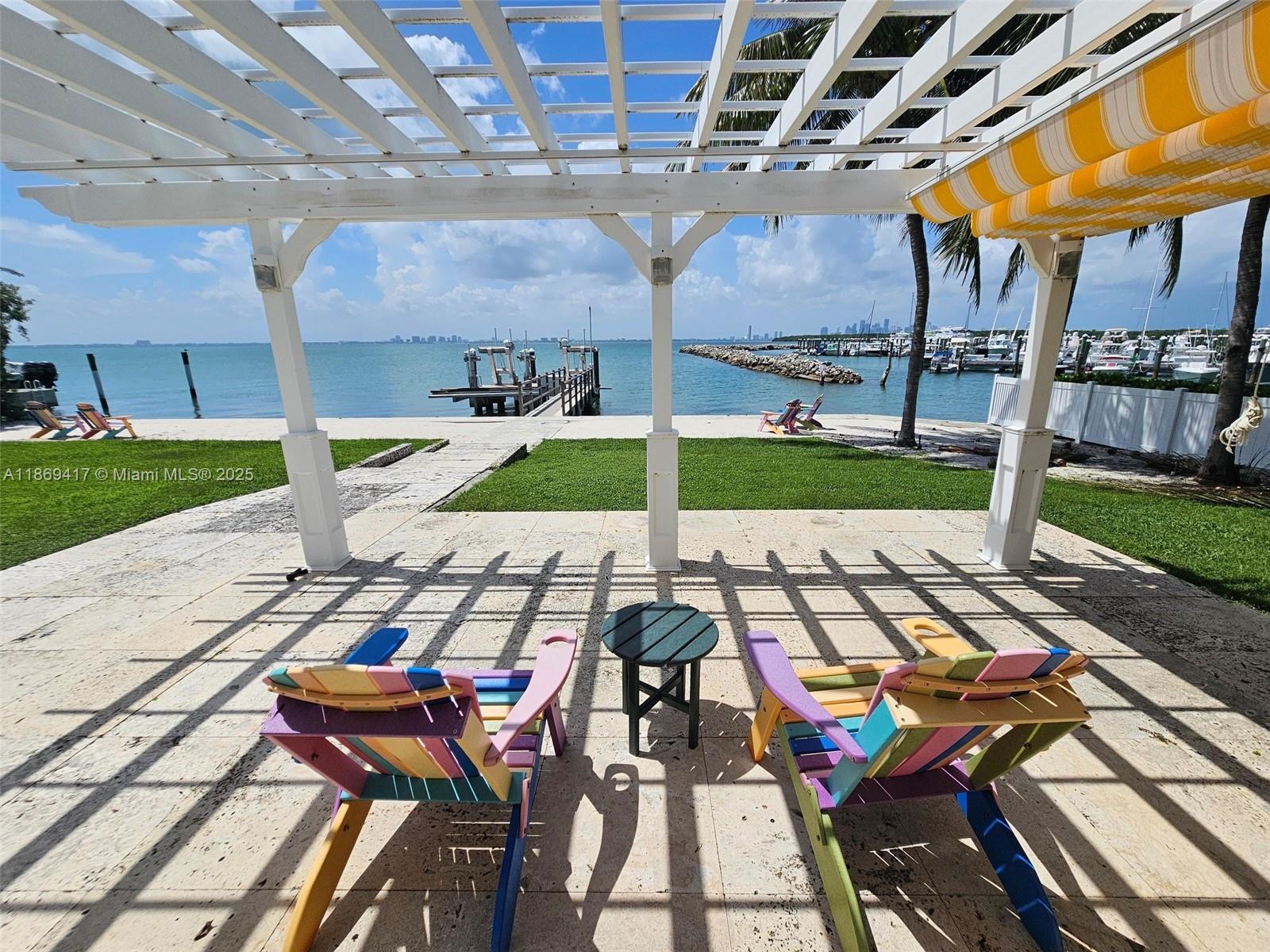A patio with a pergola, colorful chairs, and a view of the ocean and marina — 200 Harbor Dr, Key Biscayne FL 33149, KEY BISCAYNE, FL