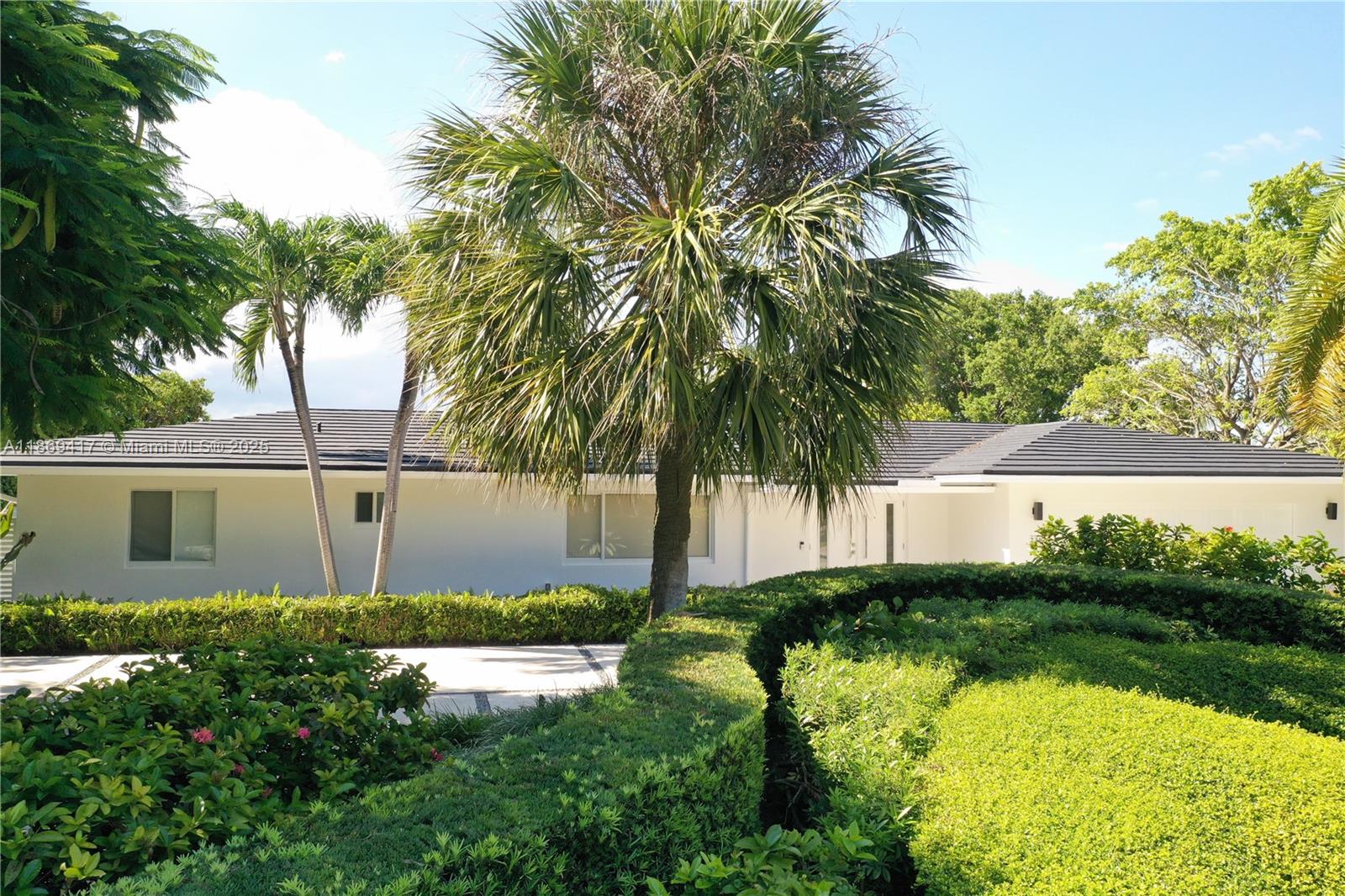 A white single-story house with a dark tiled roof is surrounded by lush green landscaping — 200 Harbor Dr, Key Biscayne FL 33149, KEY BISCAYNE, FL