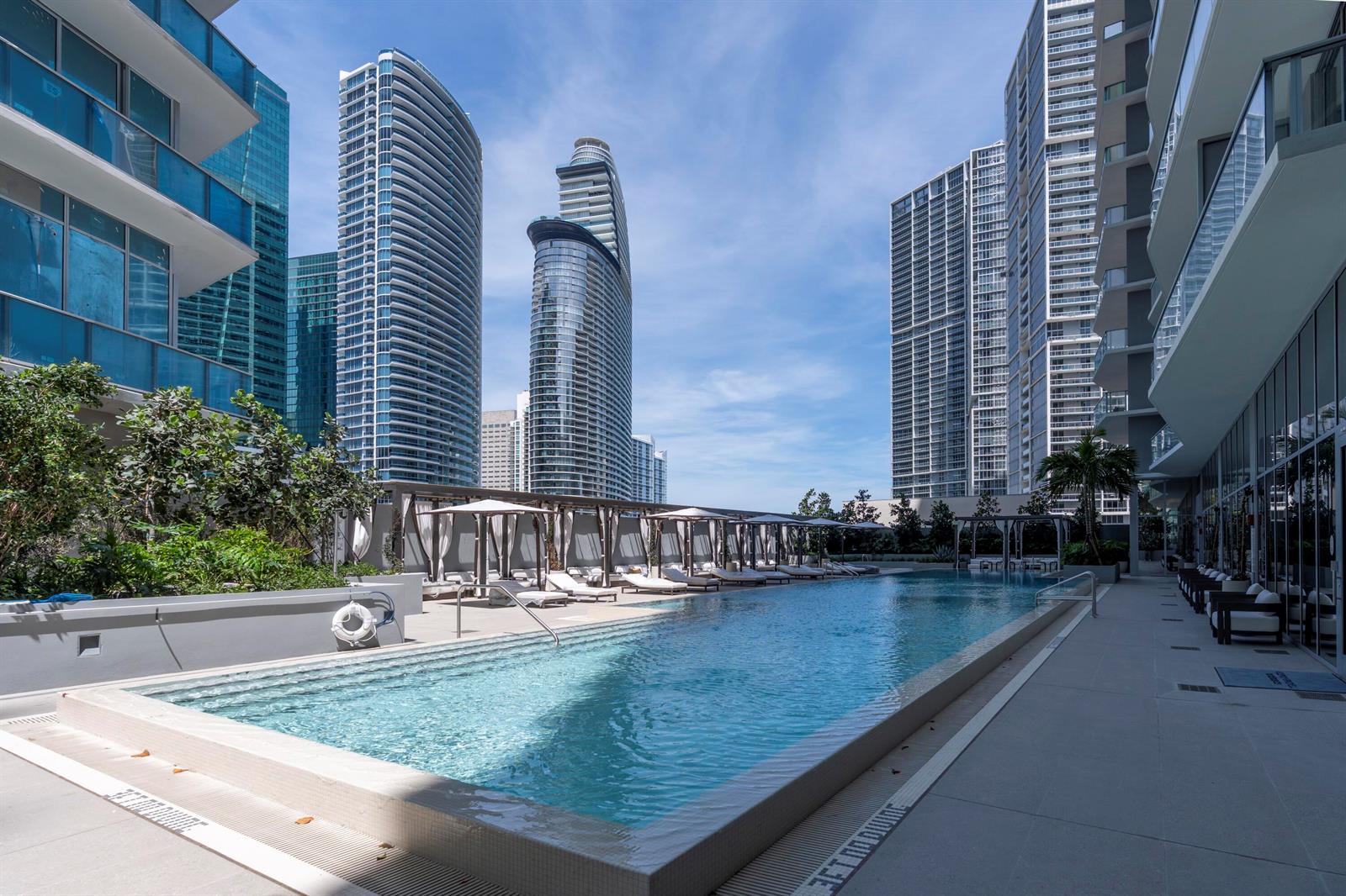 An outdoor swimming pool surrounded by lounge chairs and high-rise apartment buildings — 77 SE 5th Street # 2210, Miami FL 33131, MIAMI, FL