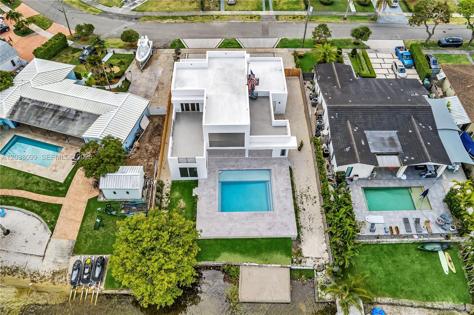 An aerial view shows a modern white house with a pool between two neighboring homes — 10755 SW 52nd Ter, Miami FL 33165, MIAMI, FL