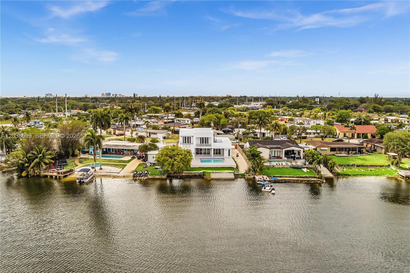 An aerial view shows a modern white house with a pool situated along a canal — 10755 SW 52nd Ter, Miami FL 33165, MIAMI, FL
