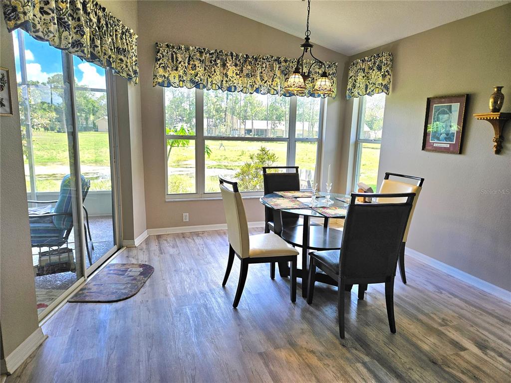 A dining area features a glass table, four chairs, a chandelier, and large windows — 11340 TEE TIME CIRCLE, NEW PORT RICHEY, FL