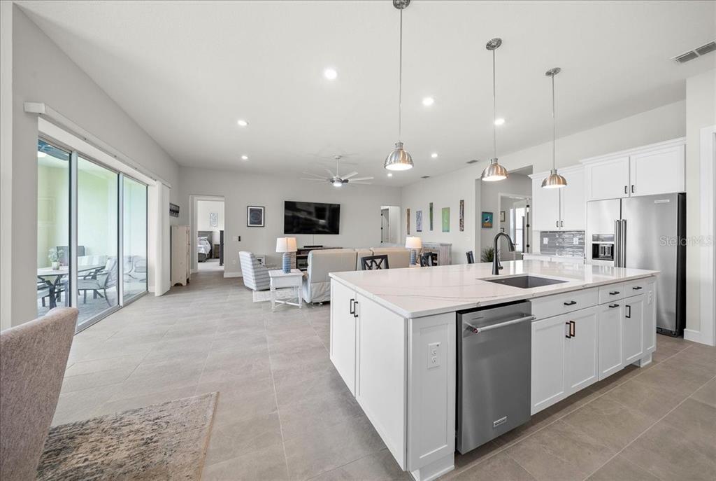 A modern open-concept kitchen and living area with white cabinetry, a large island, and tile flooring — 6015 SW 86TH CIRCLE, OCALA, FL